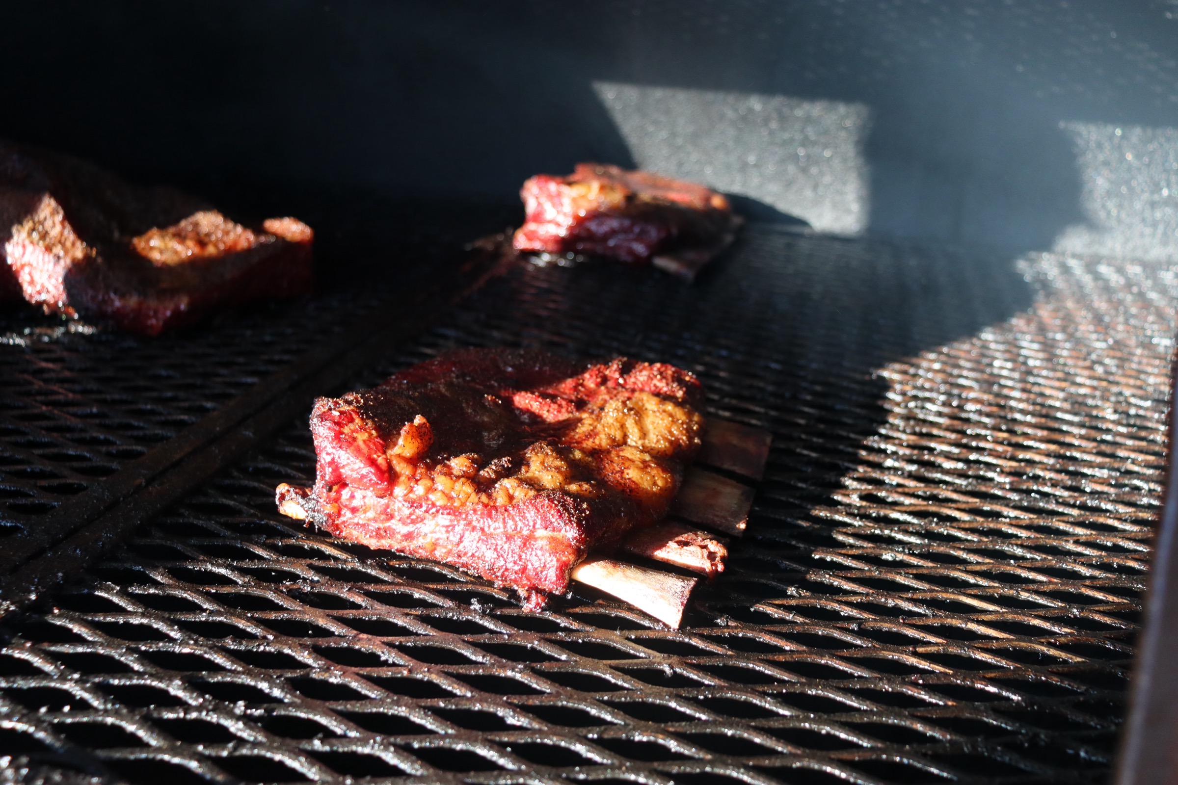 Beef ribs on the smoker, smoke billowing