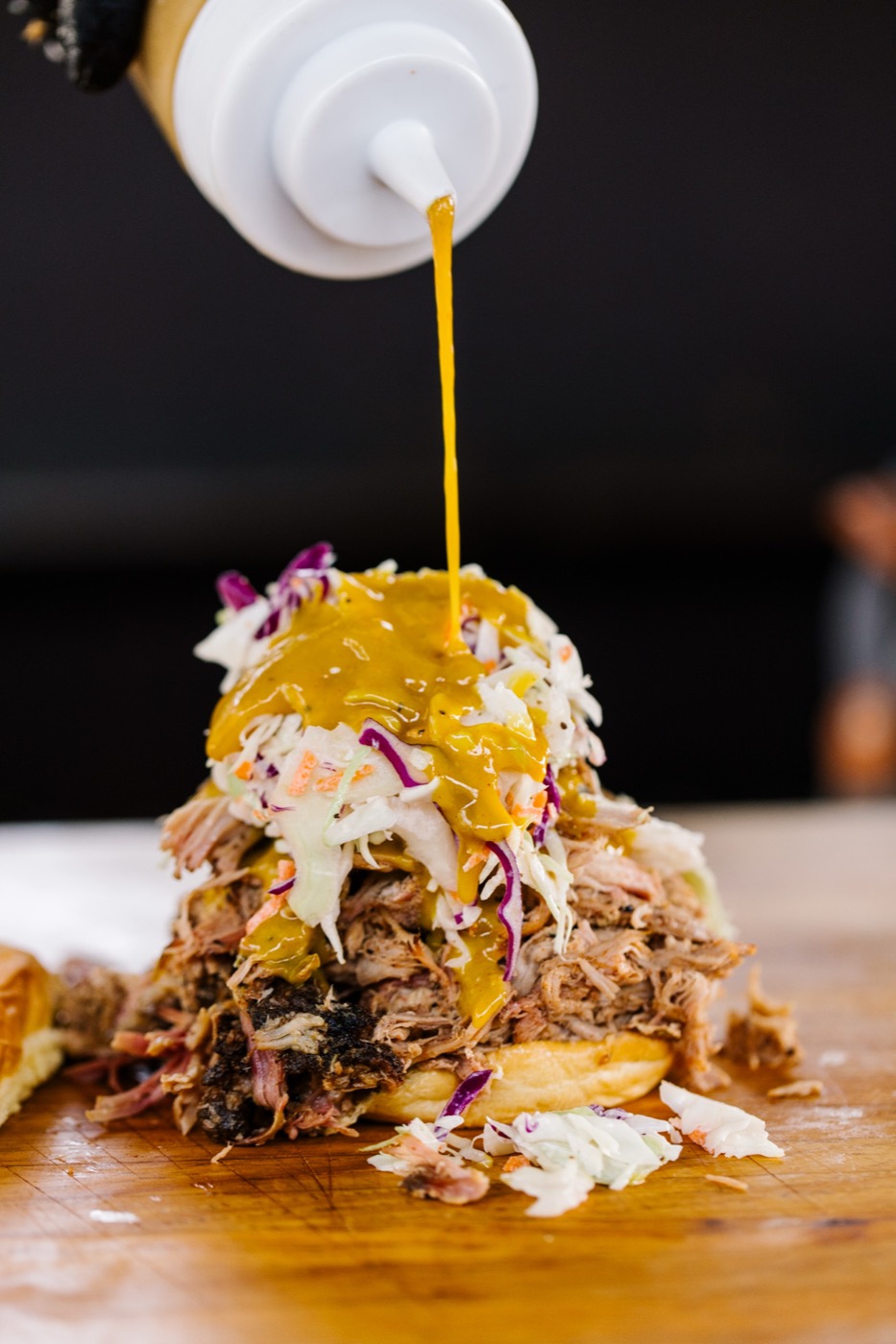 Pulled pork piled tall with slaw and mustard pour